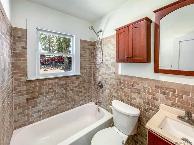 Tile-surround bathtub and shower combination with a window, single vanity with a countertop, and a wall-mounted medicine cabinet Tile-surround bathtub and shower combination with a window, single vanity with a countertop, and a wall-mounted medicine cabinet