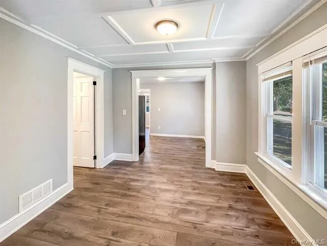 Wood-finish flooring, white trim, light gray walls, white framed windows, and a coffered ceiling Wood-finish flooring, white trim, light gray walls, white framed windows, and a coffered ceiling
