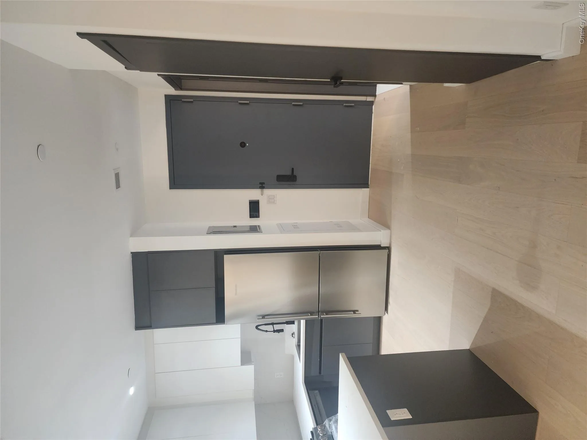 Modern kitchen featuring stainless steel appliances, two-tone cabinetry, and light wood-finish flooring Modern kitchen featuring stainless steel appliances, two-tone cabinetry, and light wood-finish flooring