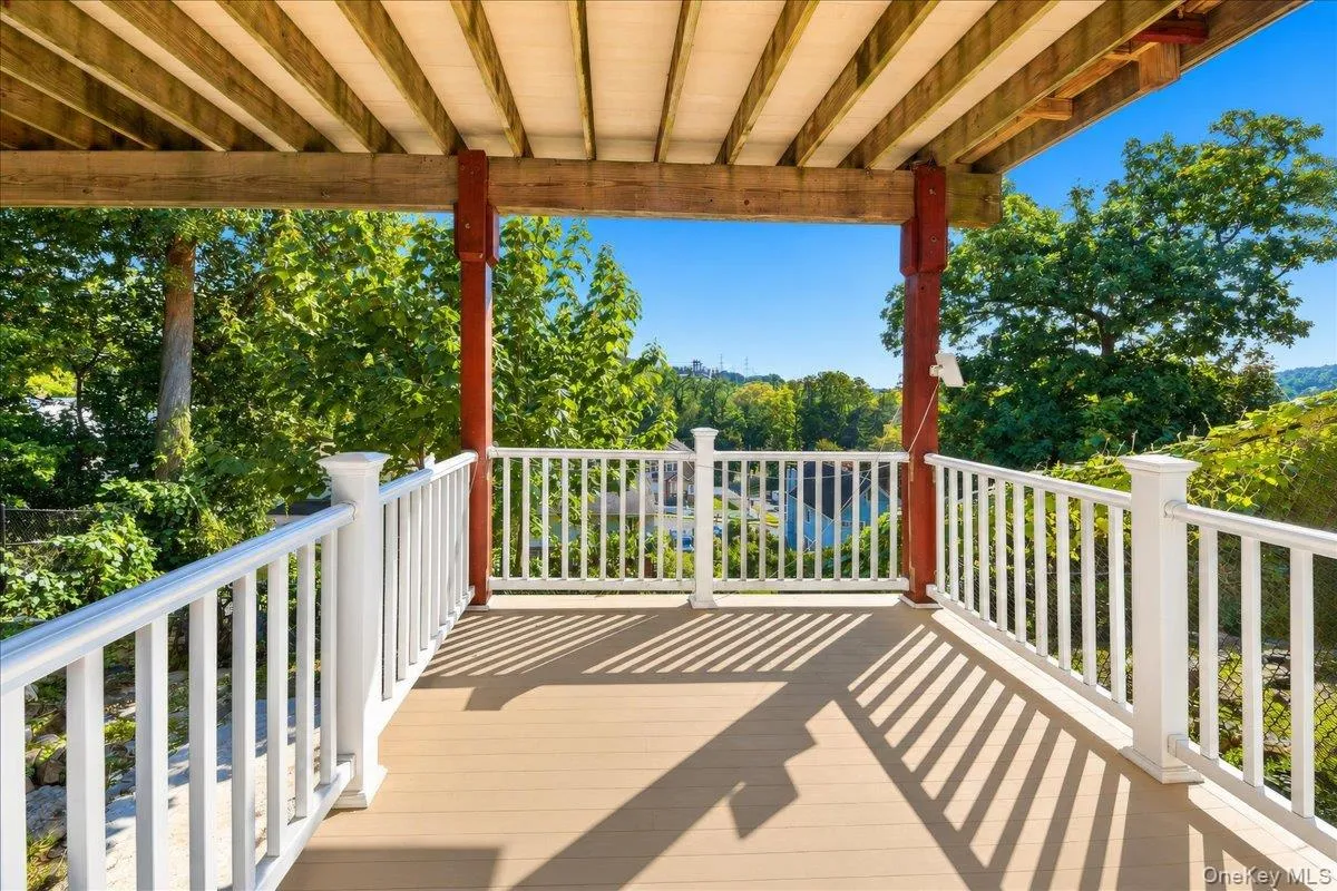 Expansive covered deck featuring a wood-finish floor and white baluster railing Expansive covered deck featuring a wood-finish floor and white baluster railing