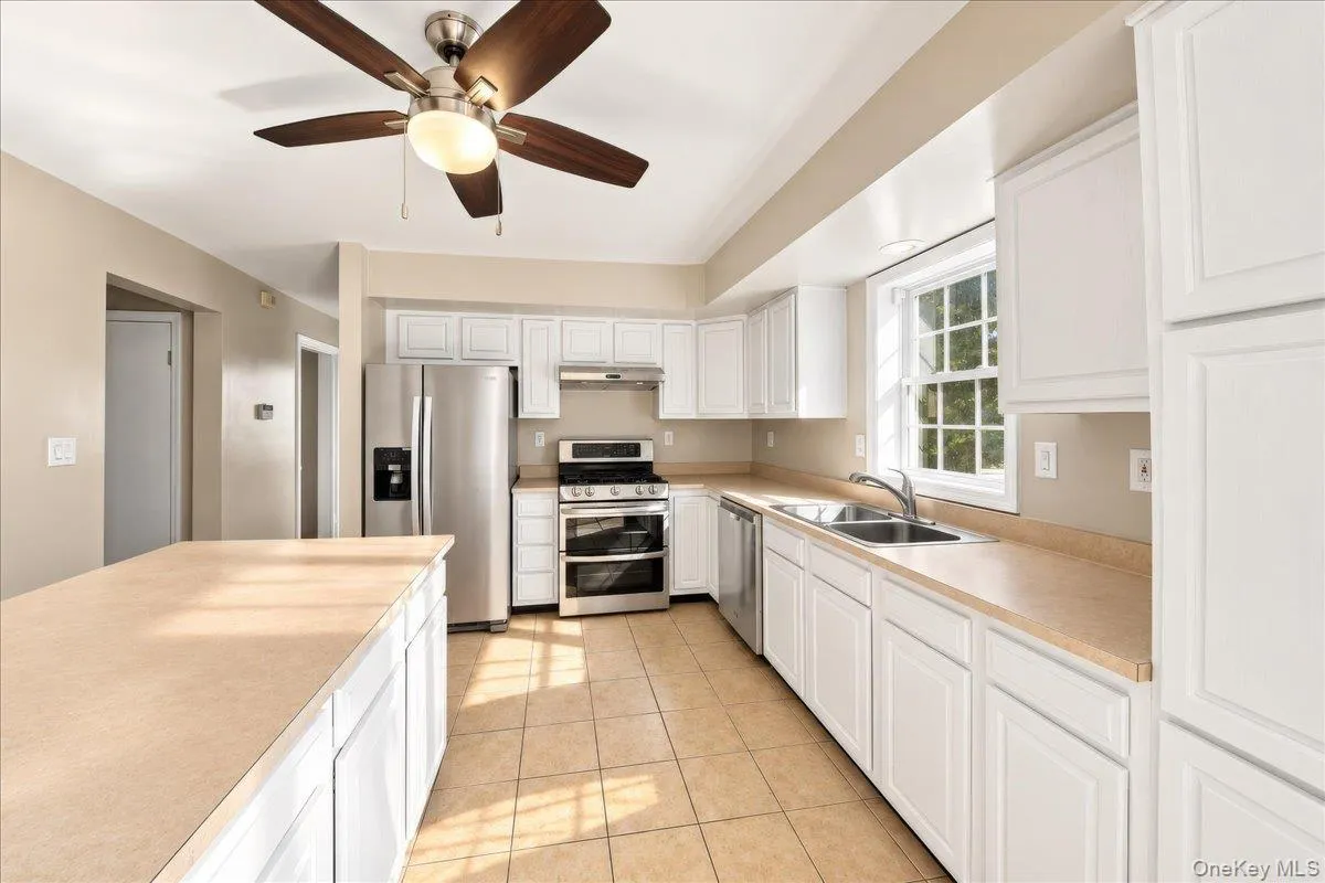 Kitchen featuring white cabinetry, light-toned countertops, stainless steel appliances, and tiled flooring Kitchen featuring white cabinetry, light-toned countertops, stainless steel appliances, and tiled flooring