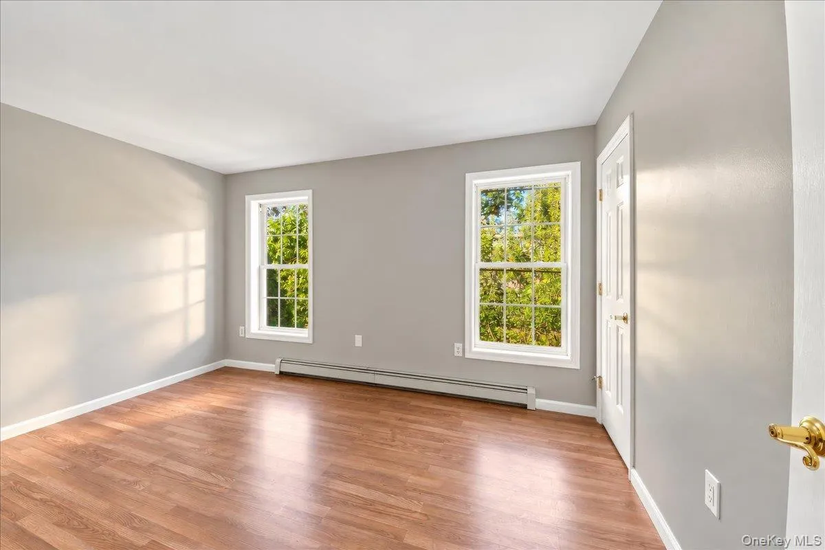 Wood-finish flooring, light gray walls, white trim, and two windows Wood-finish flooring, light gray walls, white trim, and two windows