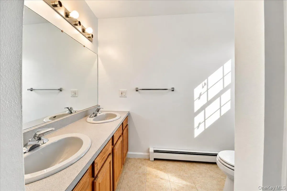 Double vanity with integral sinks, expansive mirror, and wood-finish cabinetry Double vanity with integral sinks, expansive mirror, and wood-finish cabinetry