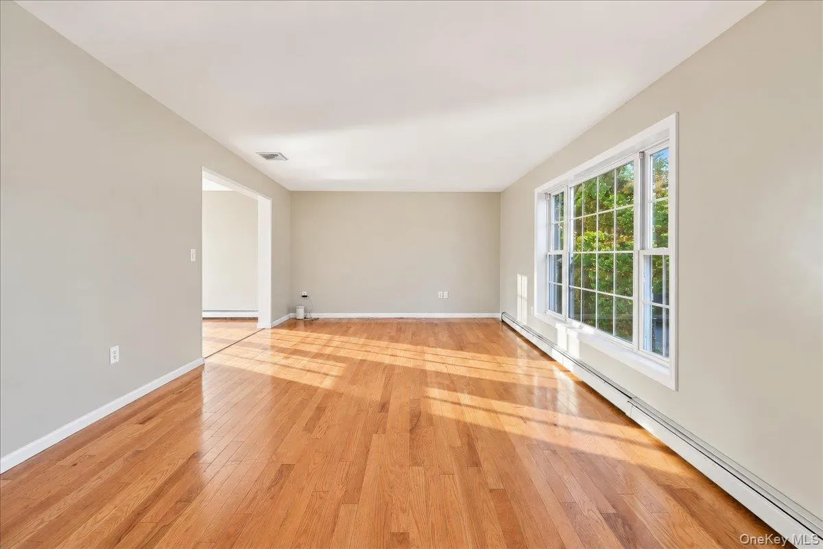 Hardwood flooring, expansive window, light neutral wall color, white trim, and baseboard heating Hardwood flooring, expansive window, light neutral wall color, white trim, and baseboard heating