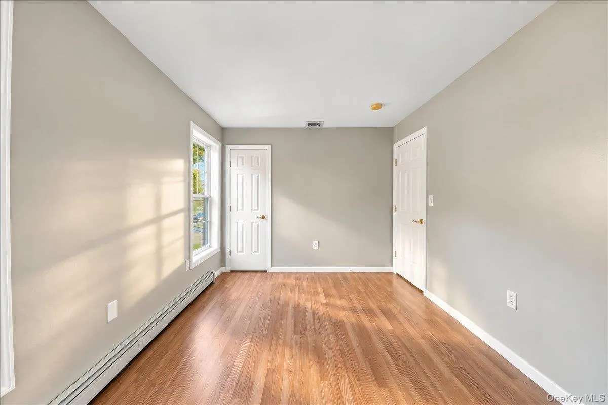 Hardwood flooring, painted walls, white trim, and a window with white casing Hardwood flooring, painted walls, white trim, and a window with white casing