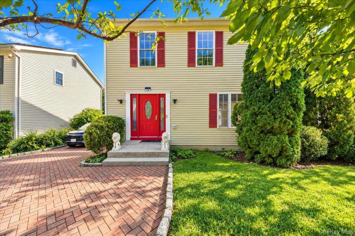 Two-story exterior with light-colored siding and red decorative shutters Two-story exterior with light-colored siding and red decorative shutters