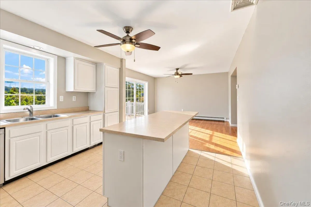 Kitchen featuring white cabinetry, a double basin sink, and an island with countertop seating Kitchen featuring white cabinetry, a double basin sink, and an island with countertop seating