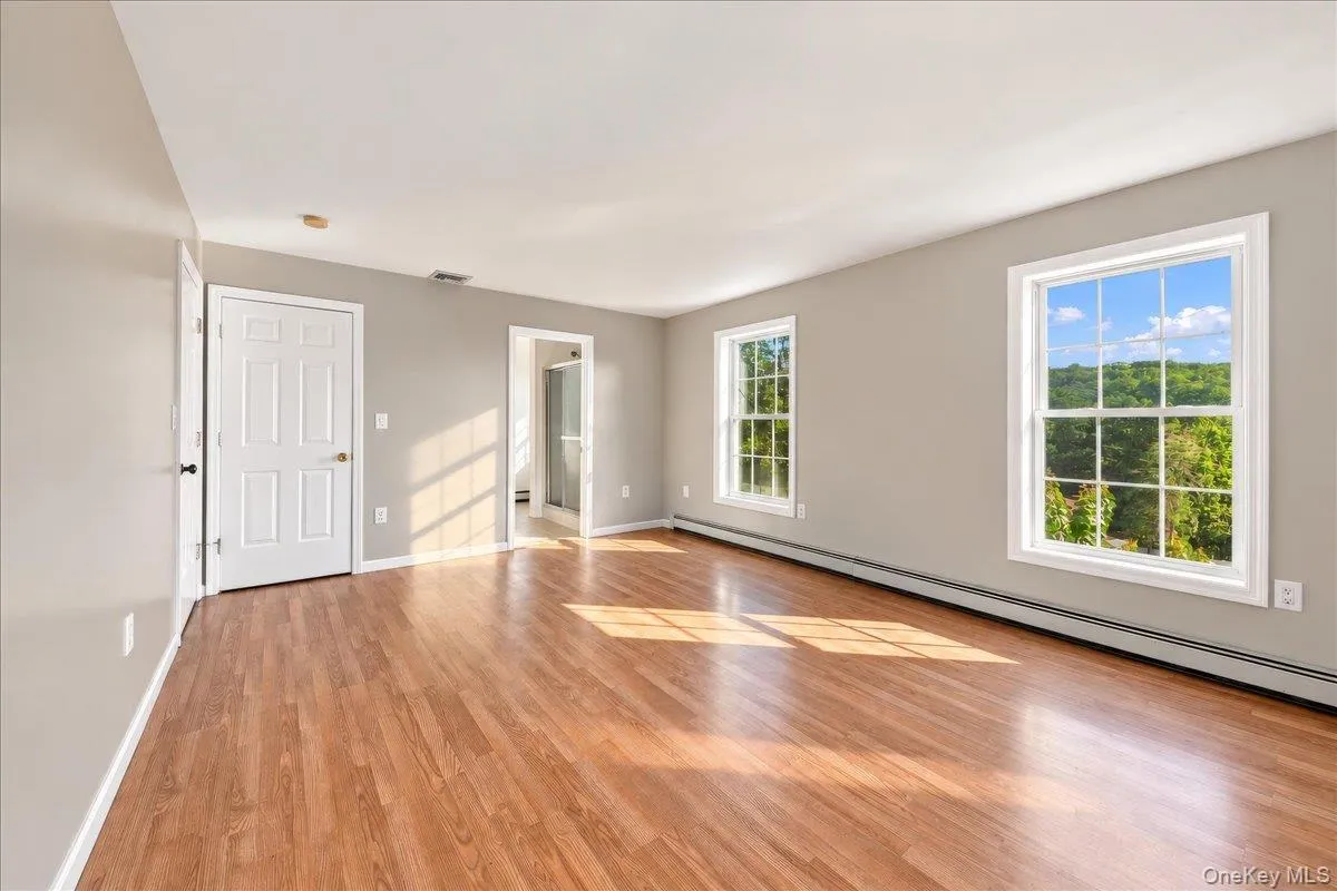 Wood-finish flooring, multiple windows, and a recessed doorway Wood-finish flooring, multiple windows, and a recessed doorway