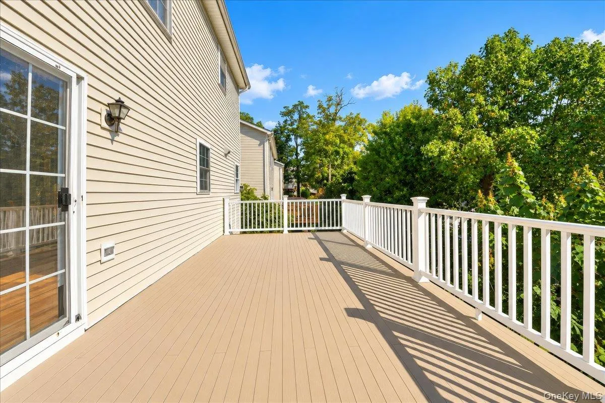 Expansive outdoor deck with composite flooring, white railing, and sliding glass door access Expansive outdoor deck with composite flooring, white railing, and sliding glass door access