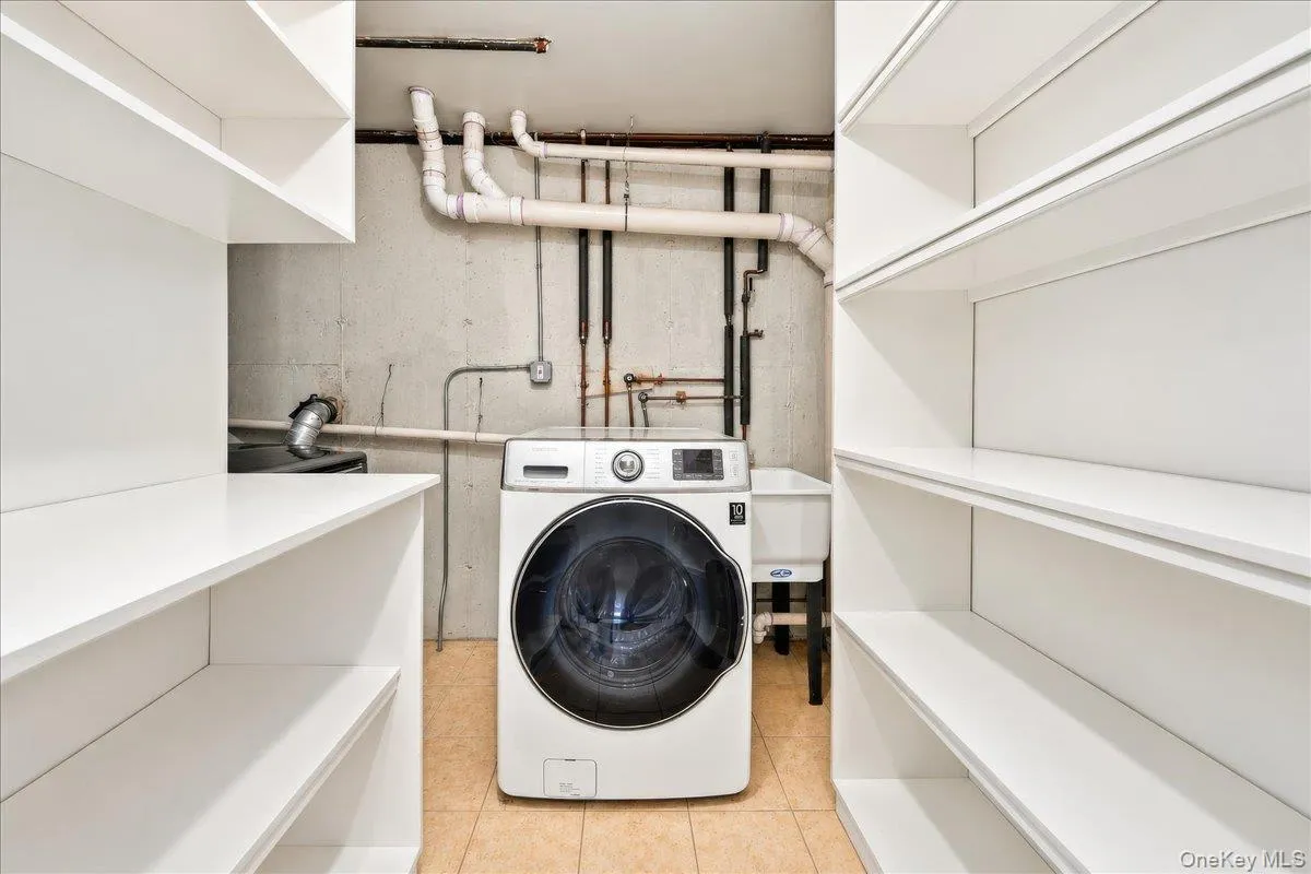 Dedicated laundry area featuring built-in shelving, a utility sink, and tiled flooring Dedicated laundry area featuring built-in shelving, a utility sink, and tiled flooring