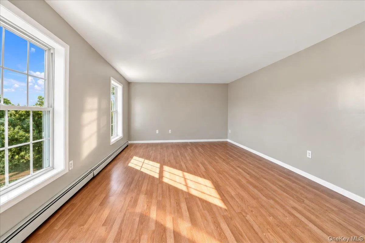 Wood-finish flooring, multiple windows with grid patterns, light neutral wall paint, and white trim Wood-finish flooring, multiple windows with grid patterns, light neutral wall paint, and white trim