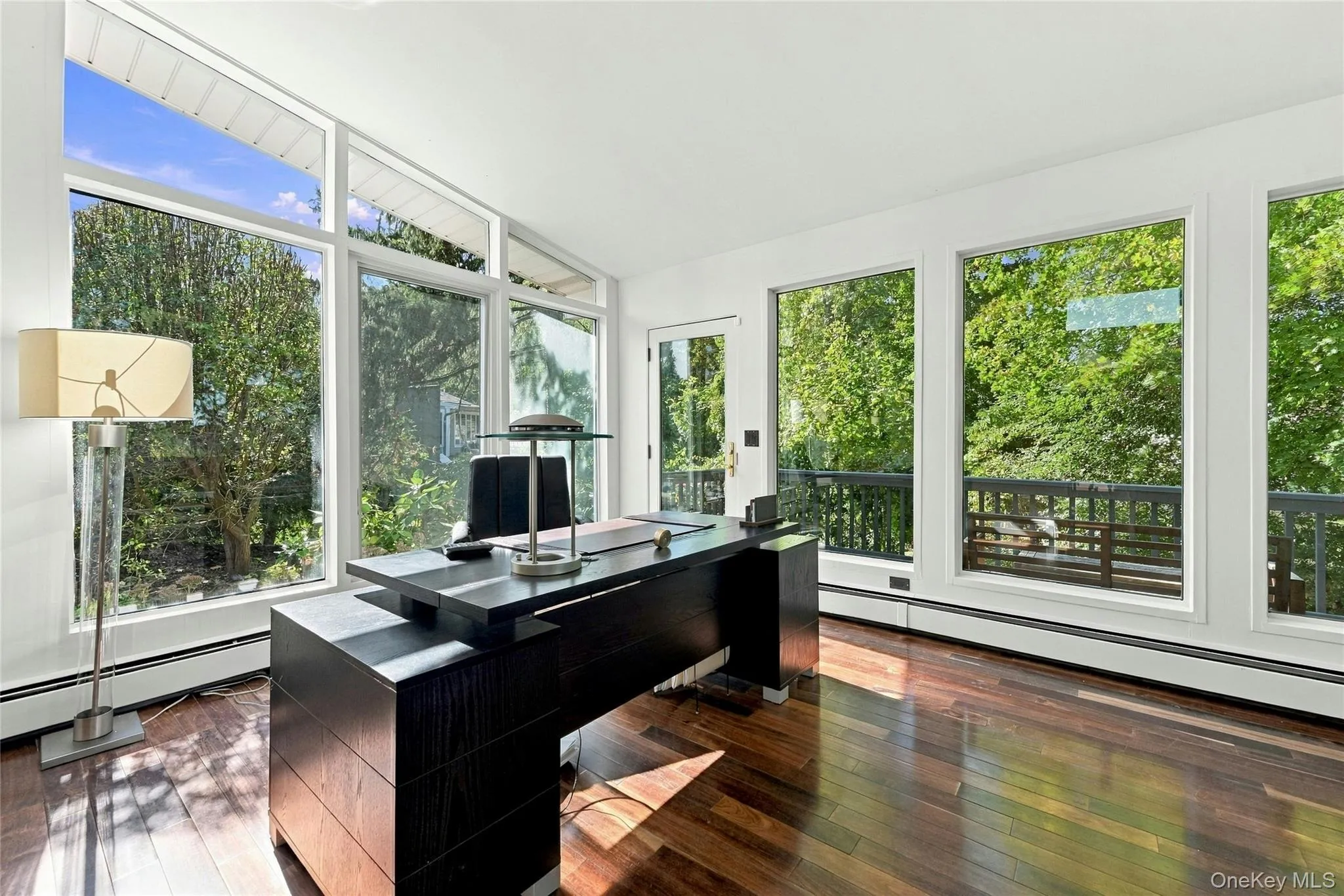 Home office featuring expansive floor-to-ceiling windows, hardwood flooring, and private deck Home office featuring expansive floor-to-ceiling windows, hardwood flooring, and private deck