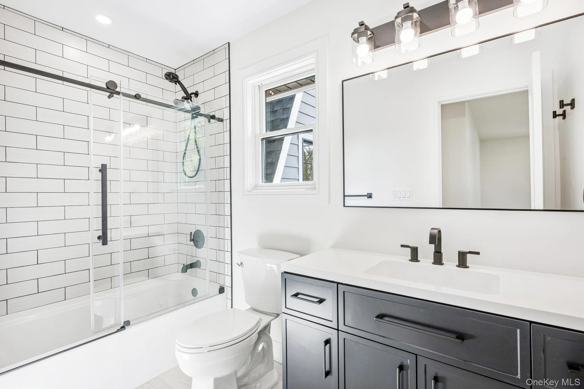 En suite bath #2 of 3 in the home - with a tiled tub and navy vanity. After sandcastles at Corey Beach and a Flo's dog at Flo's Luncheonette, both well under a mile away, bath time happens without even leaving your room. En suite bath #2 of 3 in the home - with a tiled tub and navy vanity. After sandcastles at Corey Beach and a Flo's dog at Flo's Luncheonette, both well under a mile away, bath time happens without even leaving your room.