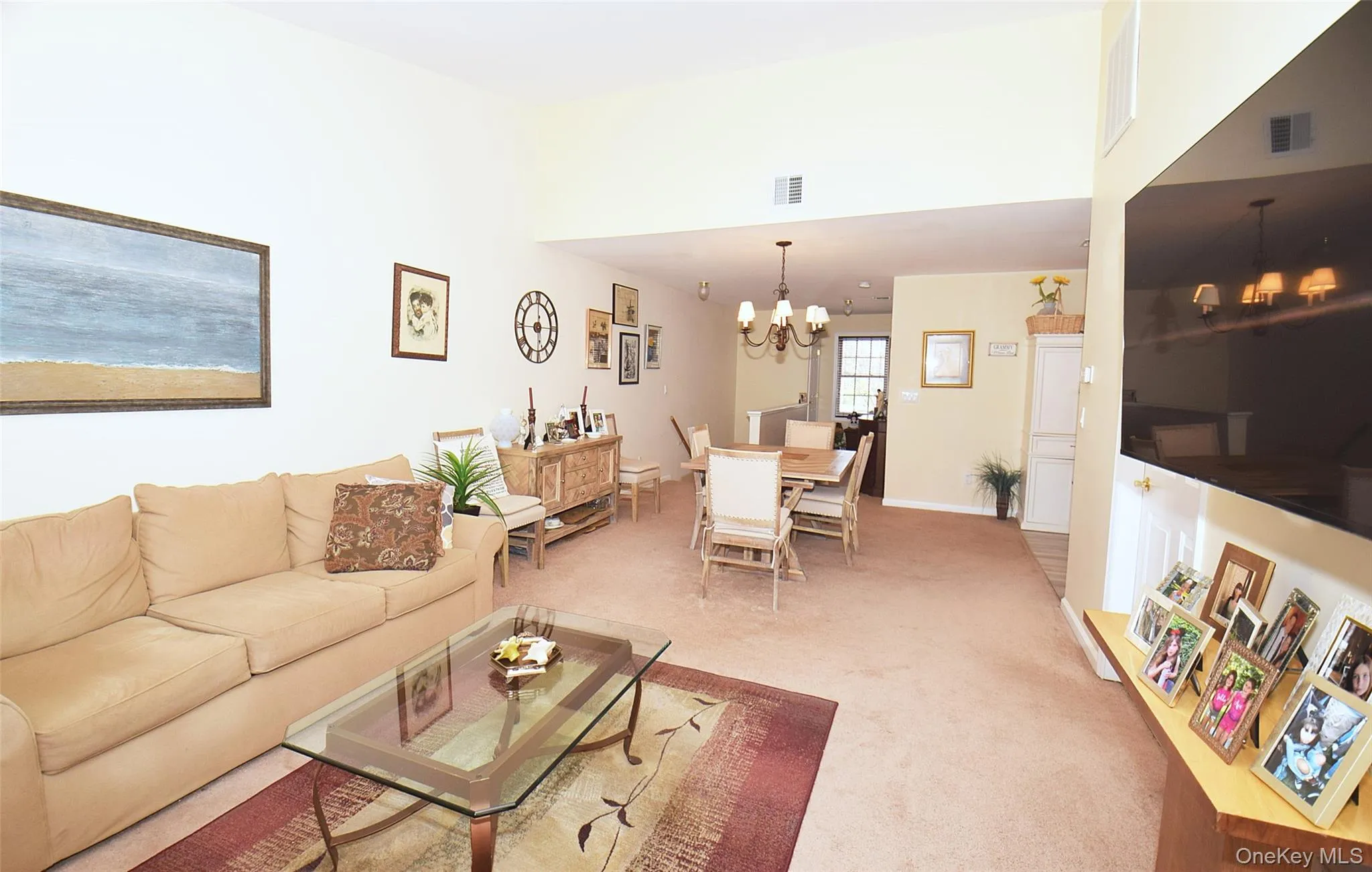 Living room with visible vents, an inviting chandelier, and light carpet Living room with visible vents, an inviting chandelier, and light carpet