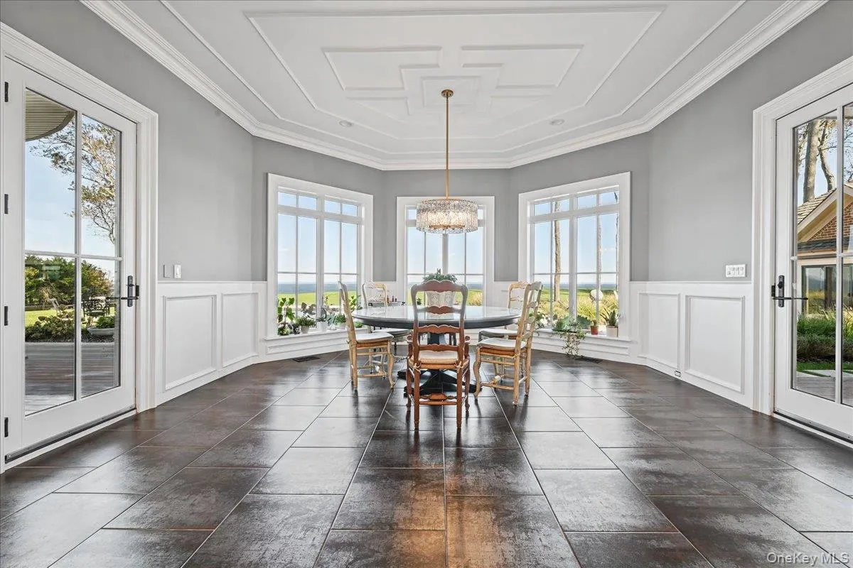 Coffered ceiling with a chandelier, wainscoting, multiple large windows, and dark tile flooring Coffered ceiling with a chandelier, wainscoting, multiple large windows, and dark tile flooring