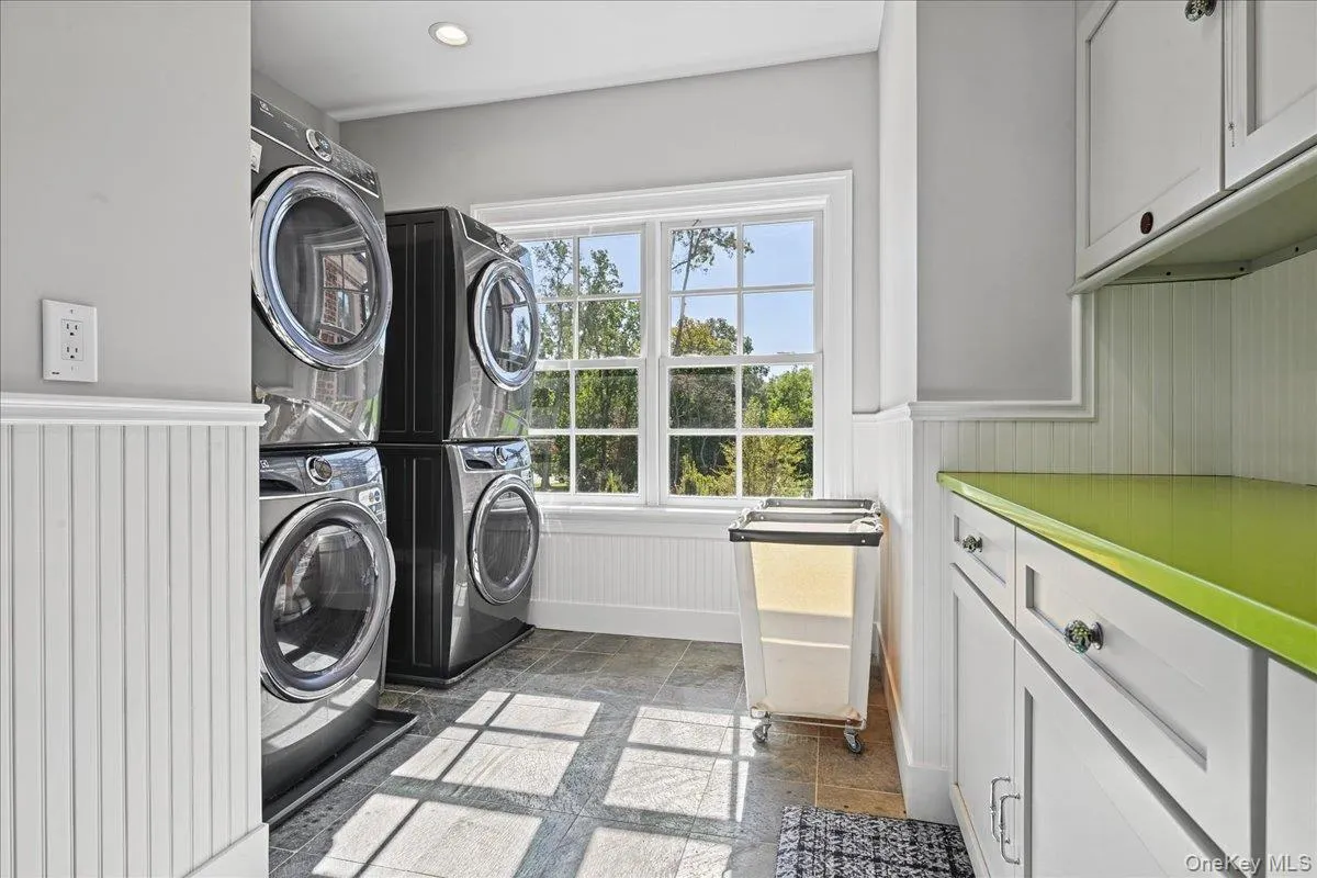 Tile flooring, window with exterior scenery, beadboard wainscoting, white cabinetry, and a bright green countertop Tile flooring, window with exterior scenery, beadboard wainscoting, white cabinetry, and a bright green countertop