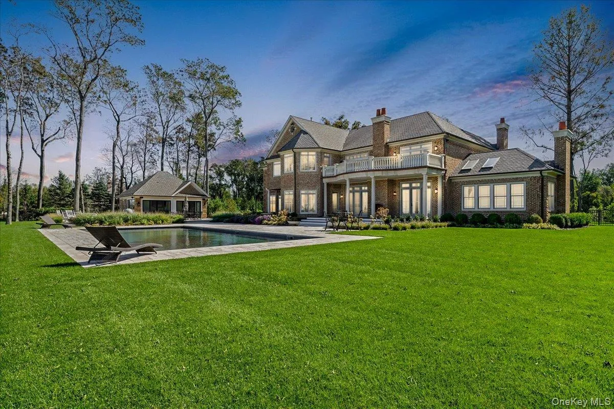 Expansive green lawn with a rectangular swimming pool, a brick exterior residence, a covered patio, and a separate cabana structure Expansive green lawn with a rectangular swimming pool, a brick exterior residence, a covered patio, and a separate cabana structure