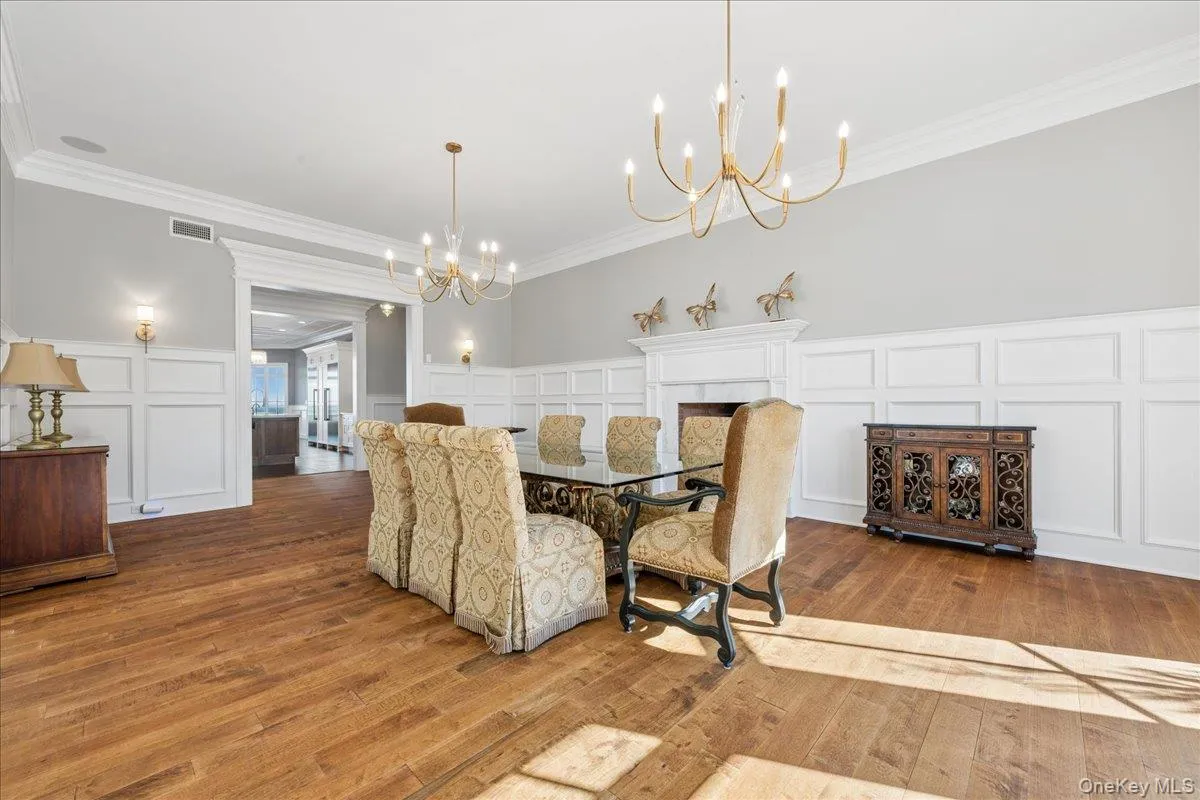Hardwood flooring, wainscoting, decorative fireplace, crown molding, and wall sconces Hardwood flooring, wainscoting, decorative fireplace, crown molding, and wall sconces
