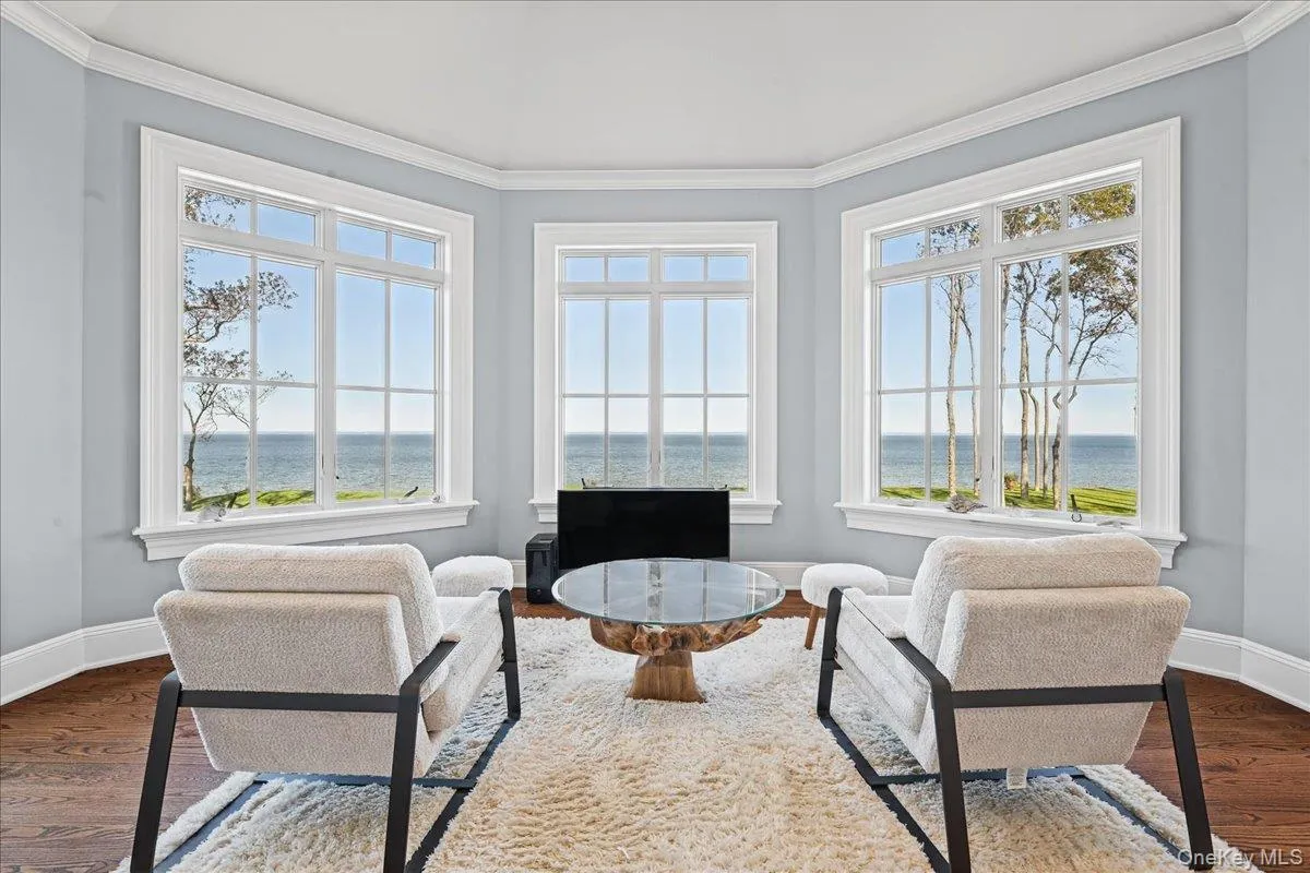 Bay window with water scenery, crown molding, and hardwood flooring Bay window with water scenery, crown molding, and hardwood flooring