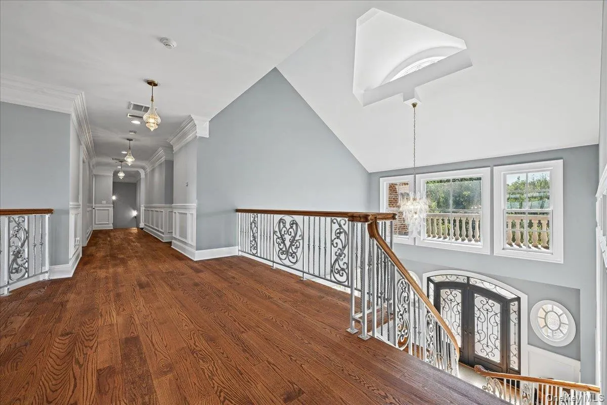 Hardwood flooring, wrought iron railing with wood-finish top, white wainscoting, recessed lighting, and a vaulted ceiling with skylight Hardwood flooring, wrought iron railing with wood-finish top, white wainscoting, recessed lighting, and a vaulted ceiling with skylight