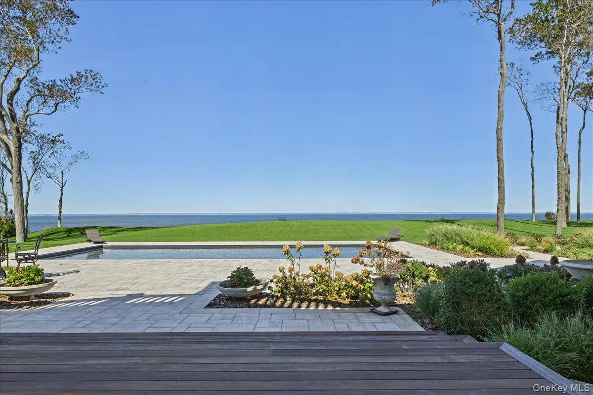 Expansive exterior with a rectangular swimming pool, surrounding paver patio, and wood-finish decking Expansive exterior with a rectangular swimming pool, surrounding paver patio, and wood-finish decking
