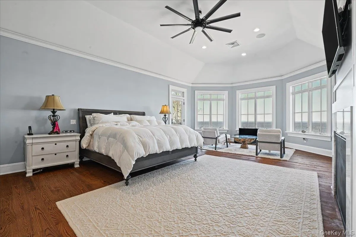 Vaulted ceiling with a contemporary ceiling fan, multiple large windows, wood-finish flooring, and crown molding Vaulted ceiling with a contemporary ceiling fan, multiple large windows, wood-finish flooring, and crown molding