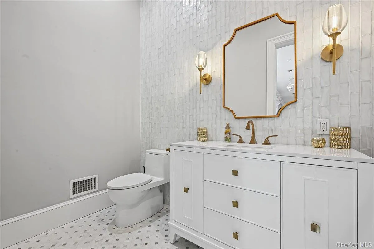 White vanity with gold-tone hardware, white countertop, and gold-tone faucet White vanity with gold-tone hardware, white countertop, and gold-tone faucet