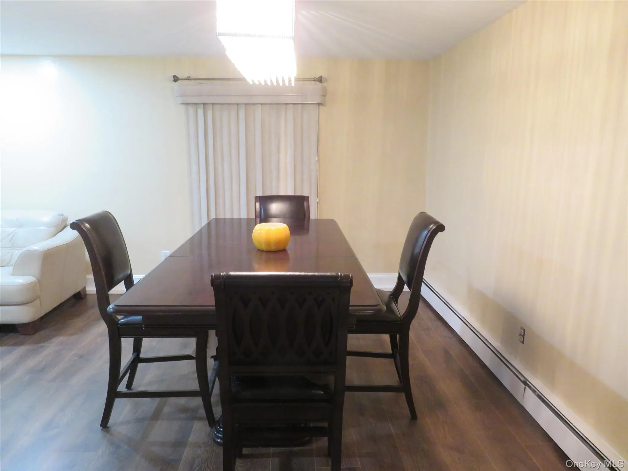Wood-finish flooring, rectangular linear pendant lighting, and vertical window blinds Wood-finish flooring, rectangular linear pendant lighting, and vertical window blinds