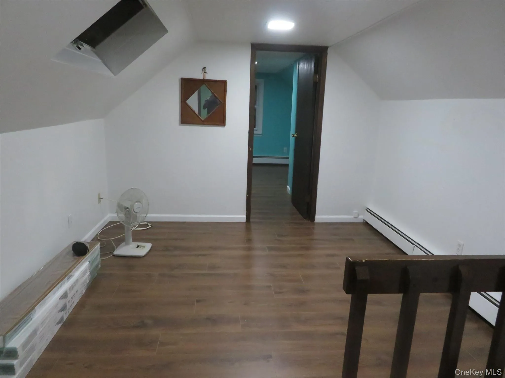 Upper-level space featuring sloped ceilings, a recessed skylight, wood-finish flooring, and a dark wood door frame Upper-level space featuring sloped ceilings, a recessed skylight, wood-finish flooring, and a dark wood door frame
