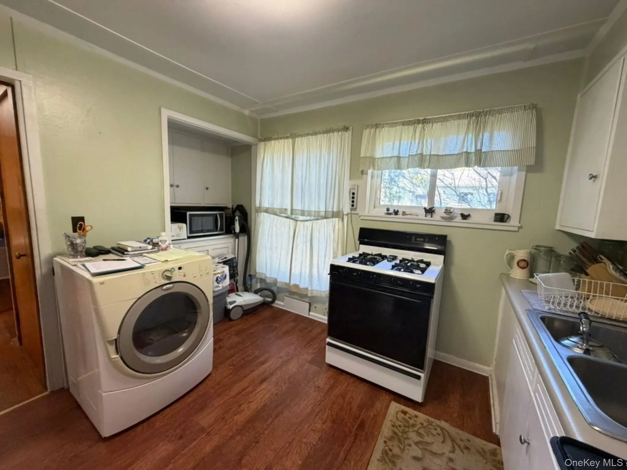 Laminate flooring, white cabinetry, and a gas range Laminate flooring, white cabinetry, and a gas range