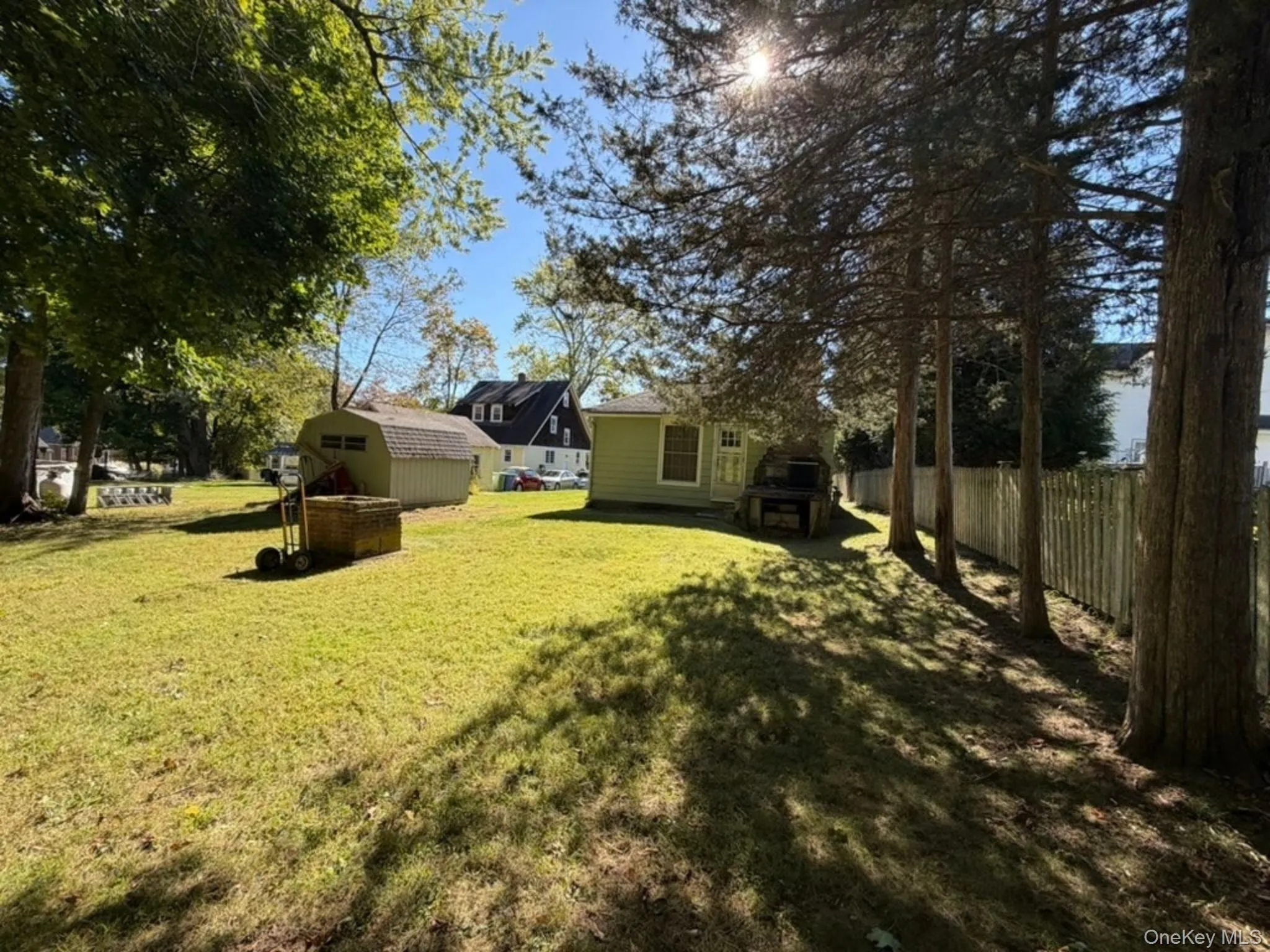 Expansive lawn area with mature trees, a detached storage shed, and a privacy fence Expansive lawn area with mature trees, a detached storage shed, and a privacy fence