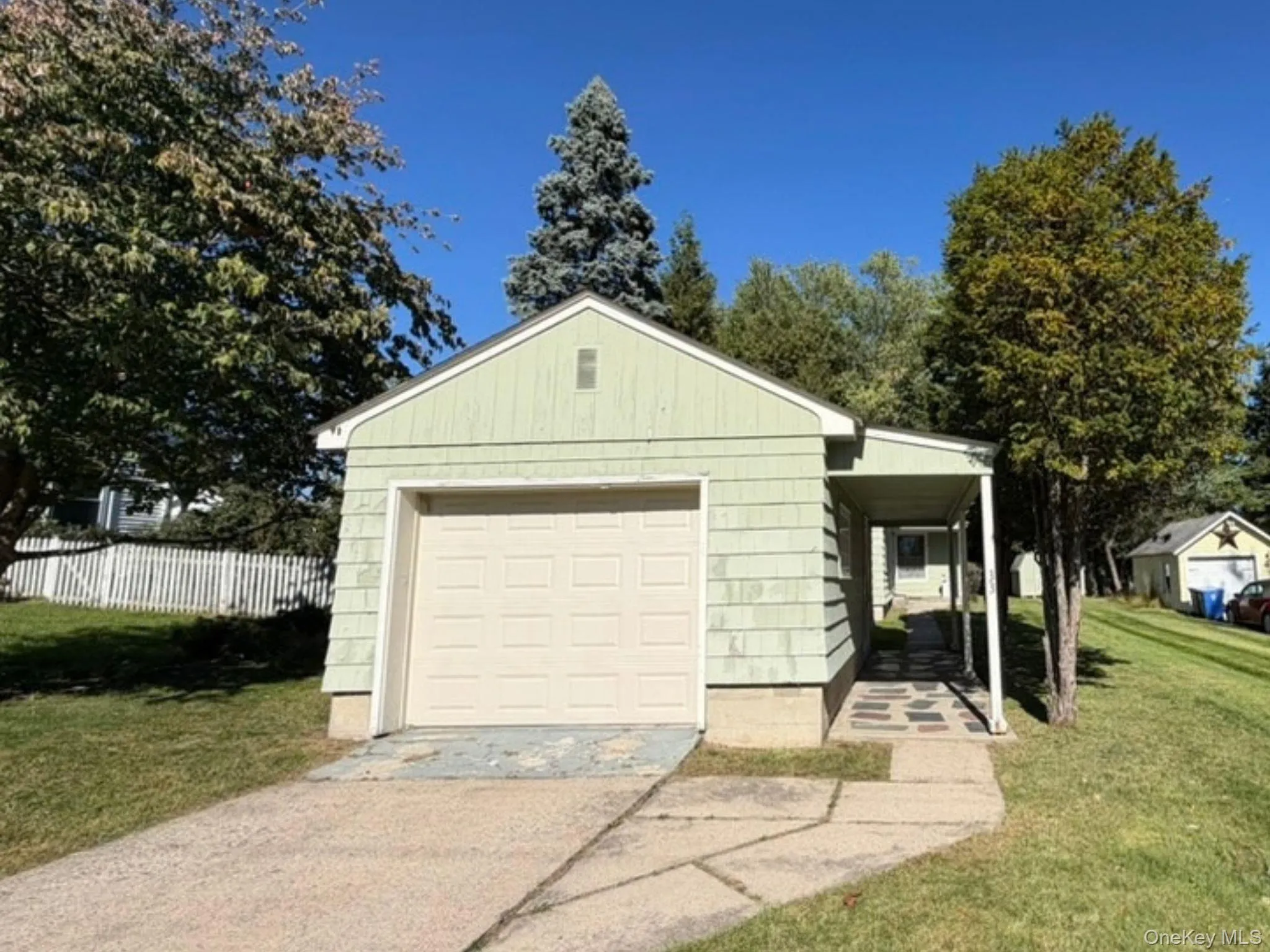 Single-car garage with a panel-style door, covered breezeway, and paved driveway Single-car garage with a panel-style door, covered breezeway, and paved driveway