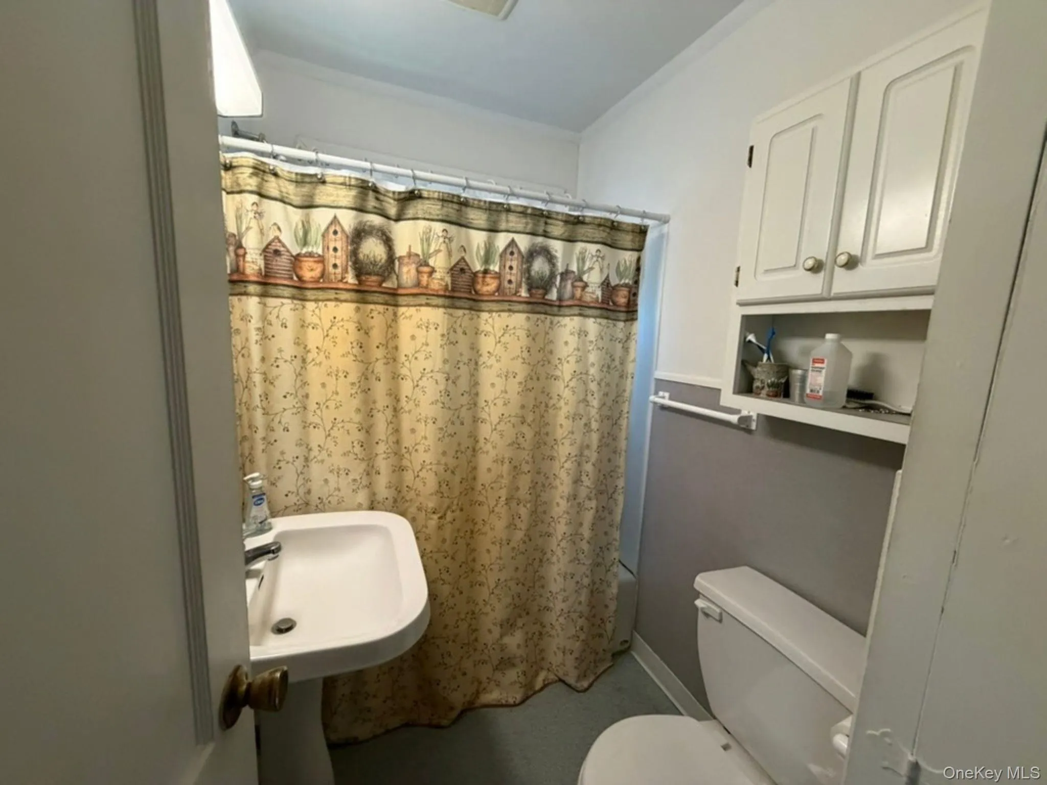 Pedestal sink with white basin, built-in wall cabinetry, and a shower with a curtain rod Pedestal sink with white basin, built-in wall cabinetry, and a shower with a curtain rod