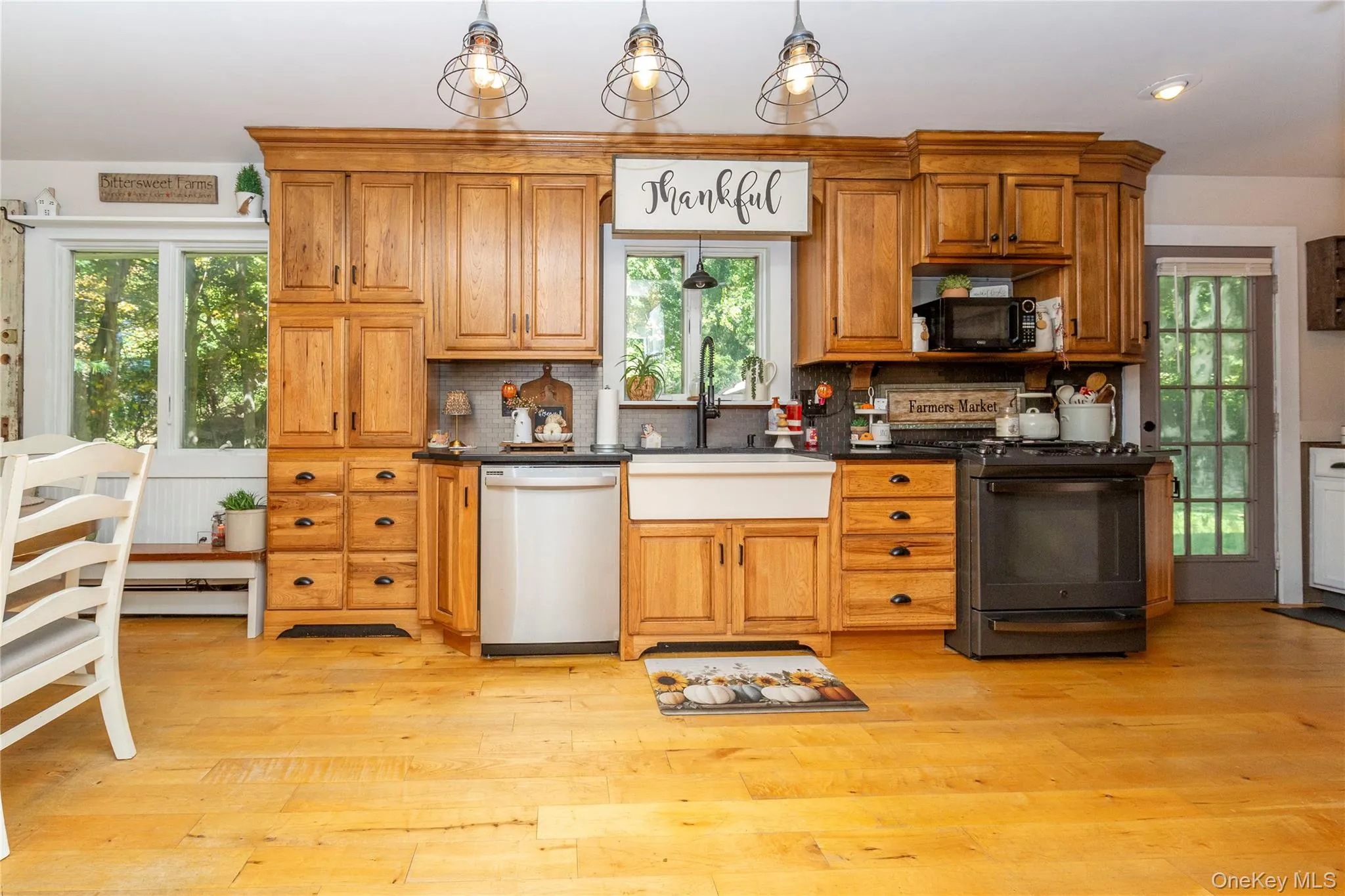 Warm honey-toned cabinetry is complemented by black granite countertops and updated stainless steel and black appliances. Warm honey-toned cabinetry is complemented by black granite countertops and updated stainless steel and black appliances.