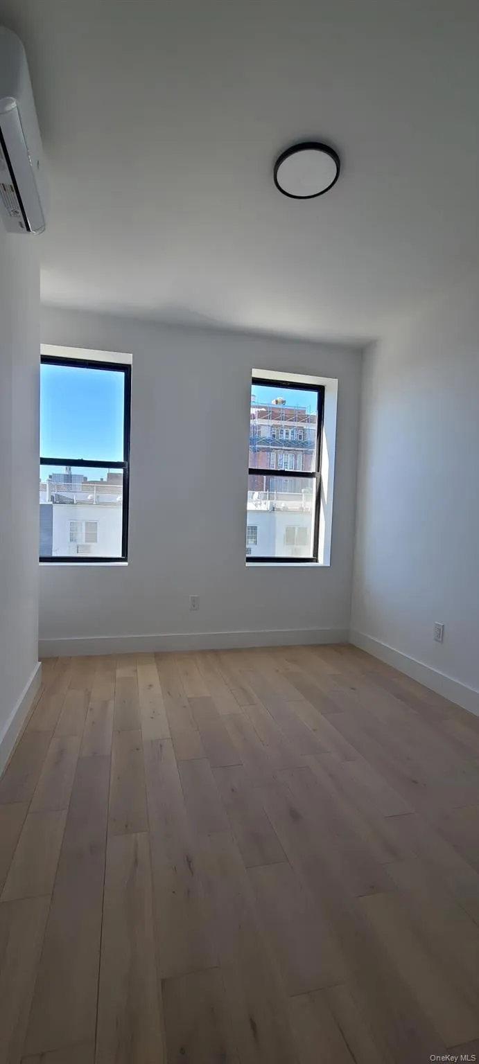 Light wood-finish flooring, two large windows, white walls, and contemporary ceiling light fixture Light wood-finish flooring, two large windows, white walls, and contemporary ceiling light fixture