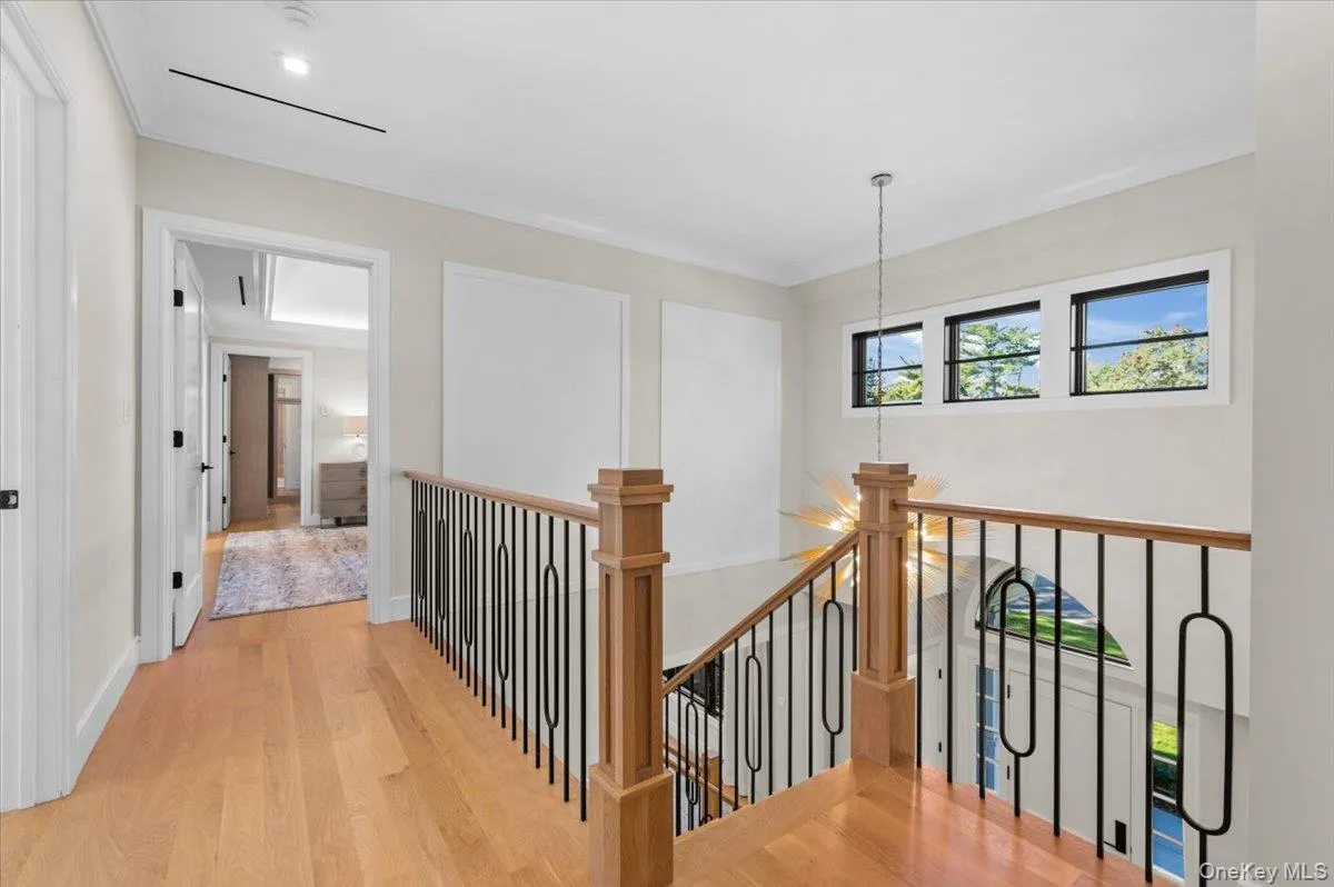 Hardwood flooring, wood newel post, black wrought iron balusters, recessed lighting, and white trim molding Hardwood flooring, wood newel post, black wrought iron balusters, recessed lighting, and white trim molding
