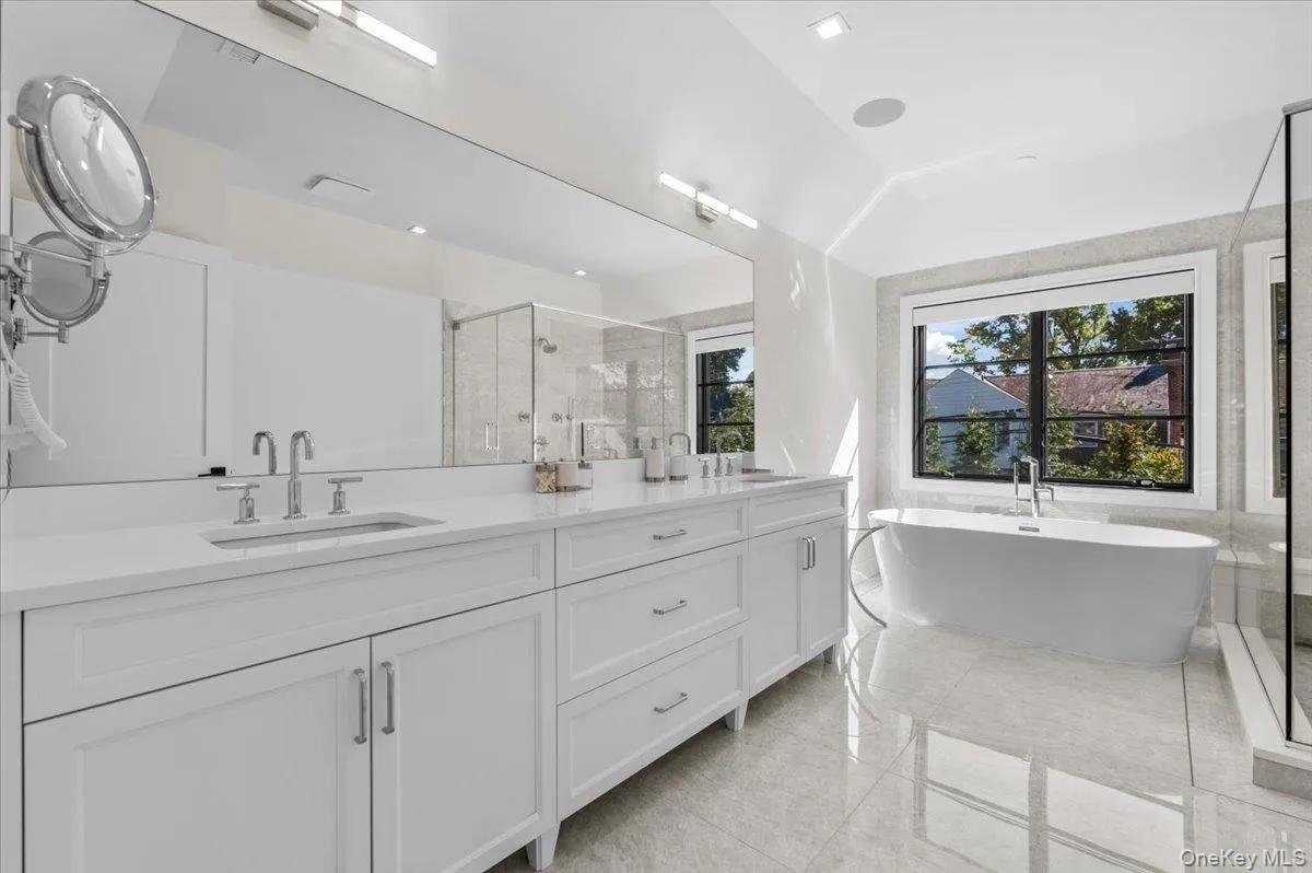 Dual vanity with white cabinetry, polished chrome fixtures, and a large integrated mirror Dual vanity with white cabinetry, polished chrome fixtures, and a large integrated mirror