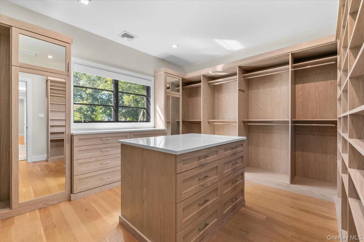 Custom wood-finish cabinetry, built-in shelving, integrated drawers, central island with countertop, and wood-finish flooring Custom wood-finish cabinetry, built-in shelving, integrated drawers, central island with countertop, and wood-finish flooring