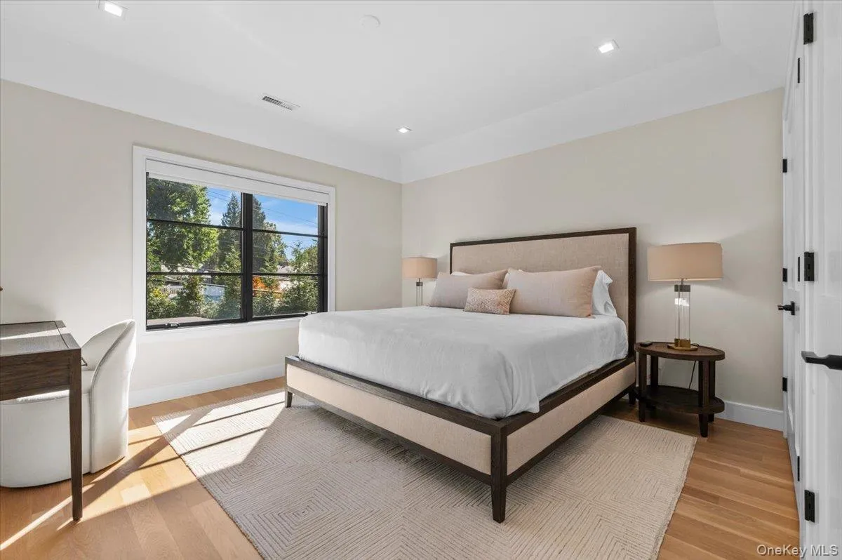 Recessed lighting, wood-finish flooring, and a large window with black framing Recessed lighting, wood-finish flooring, and a large window with black framing