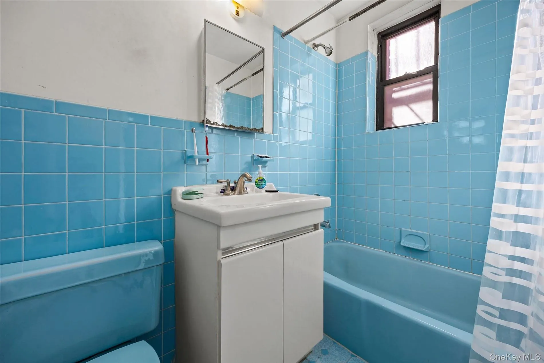 Blue tiled bath with matching tub, toilet, and flooring Blue tiled bath with matching tub, toilet, and flooring