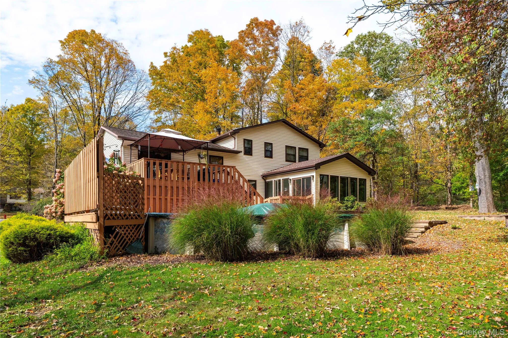 Expansive rear yard with a tiered wood-plank deck, stone-stepped pathway, and 4-Season Room Expansive rear yard with a tiered wood-plank deck, stone-stepped pathway, and 4-Season Room