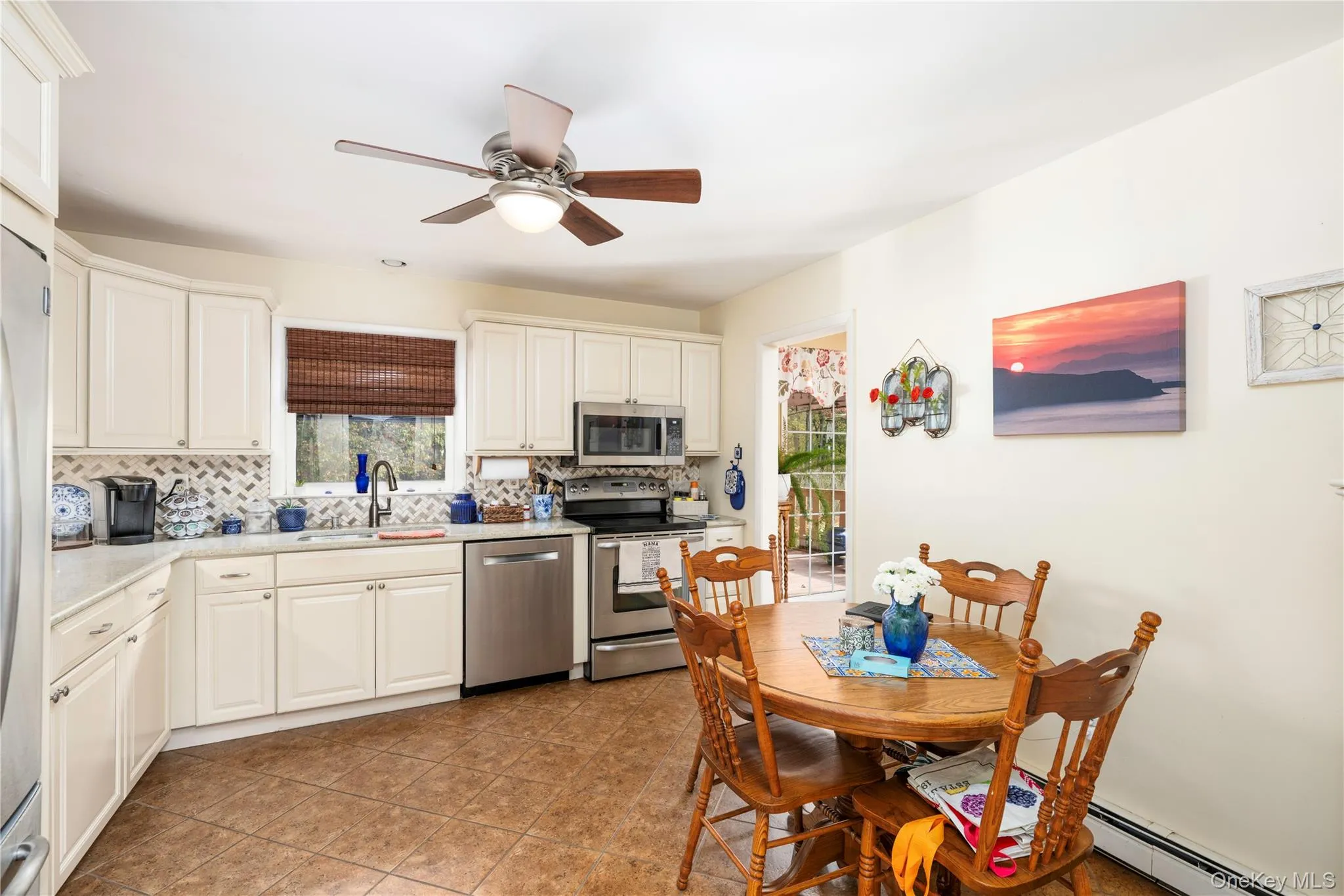 Kitchen featuring white cabinetry, stainless steel appliances, quartz counters, a herringbone-pattern tile backsplash, and a central ceiling fan with integrated lighting Kitchen featuring white cabinetry, stainless steel appliances, quartz counters, a herringbone-pattern tile backsplash, and a central ceiling fan with integrated lighting