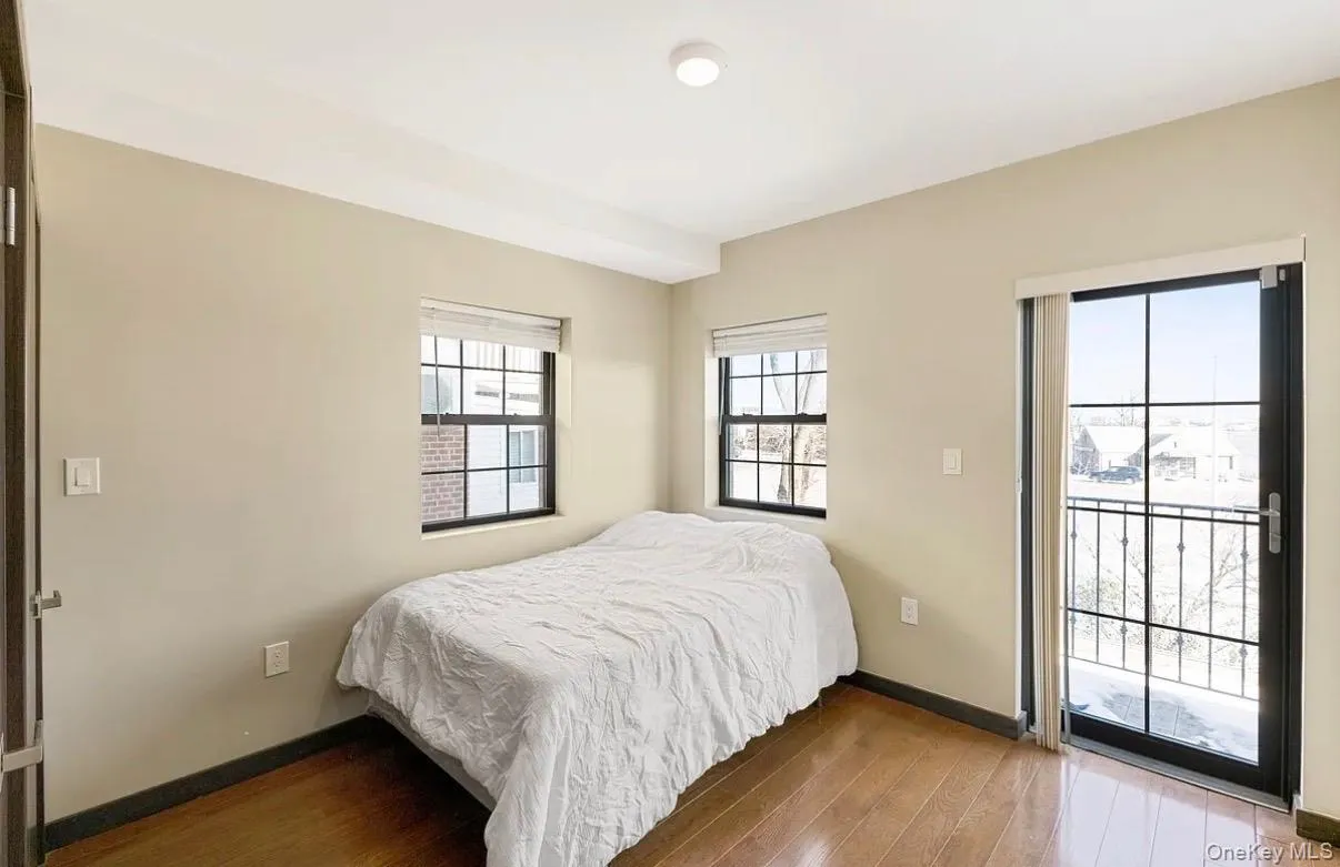 Hardwood-finish flooring, recessed ceiling lighting, two windows with blinds, and a glass-paneled exterior door with an iron balcony Hardwood-finish flooring, recessed ceiling lighting, two windows with blinds, and a glass-paneled exterior door with an iron balcony