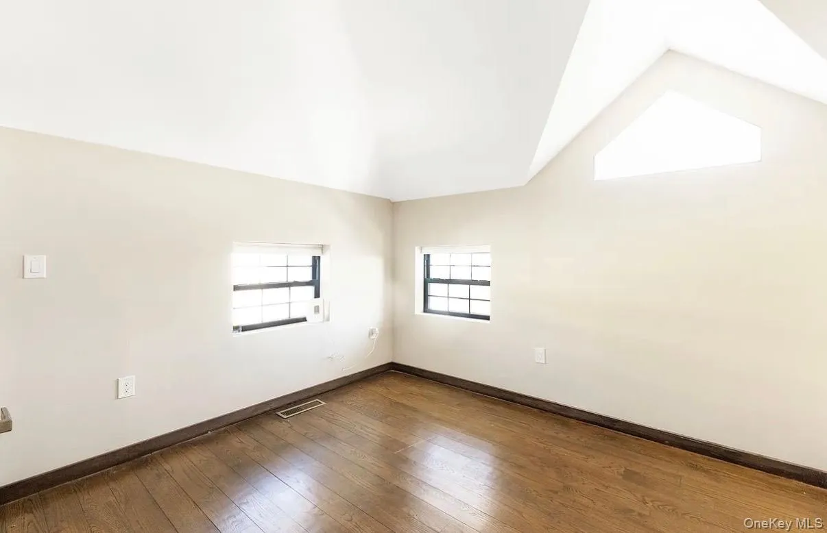 Vaulted ceiling with a trapezoidal window, wood-finish flooring, and multiple wall-mounted windows Vaulted ceiling with a trapezoidal window, wood-finish flooring, and multiple wall-mounted windows