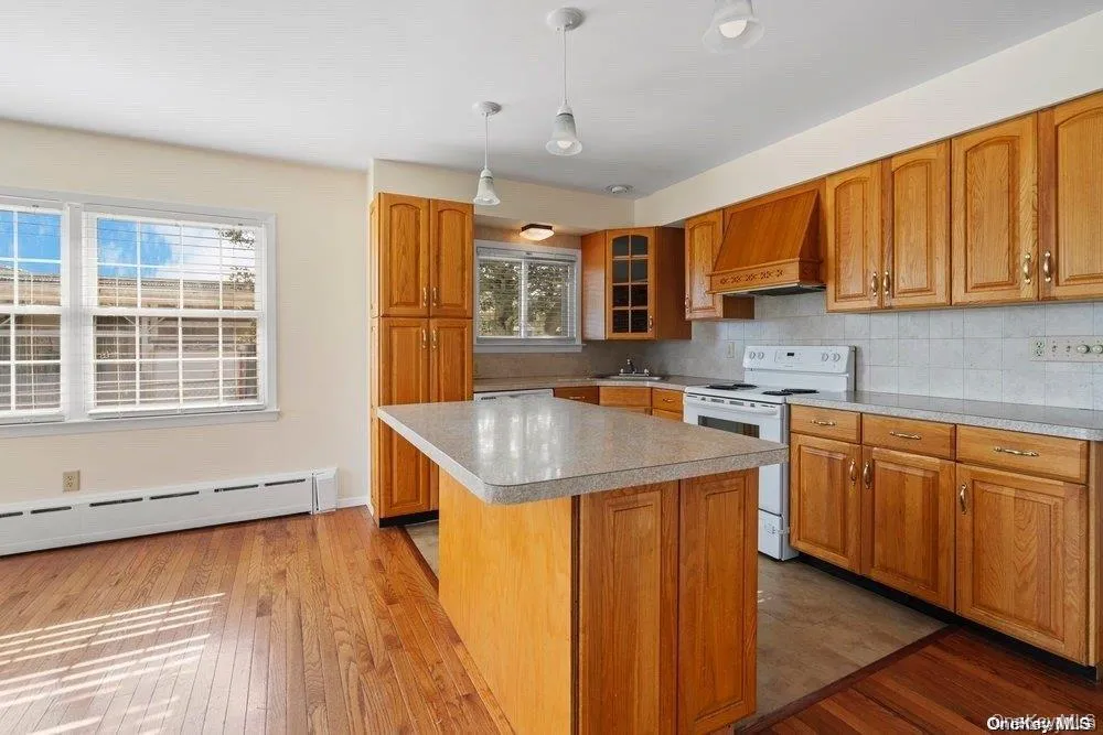 Kitchen featuring tasteful backsplash, white electric range, light countertops, and wood cabinets Kitchen featuring tasteful backsplash, white electric range, light countertops, and wood cabinets