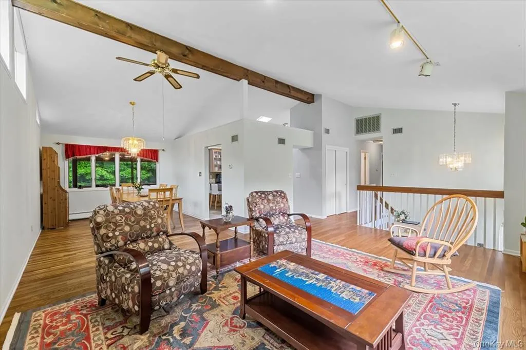Living room with a chandelier, wood finished floors, high vaulted ceiling, a ceiling fan, and beamed ceiling Living room with a chandelier, wood finished floors, high vaulted ceiling, a ceiling fan, and beamed ceiling