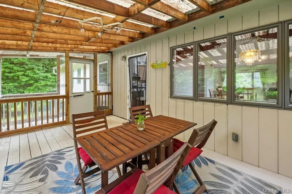 Sunroom featuring outdoor dining area, a chandelier, and a deck Sunroom featuring outdoor dining area, a chandelier, and a deck