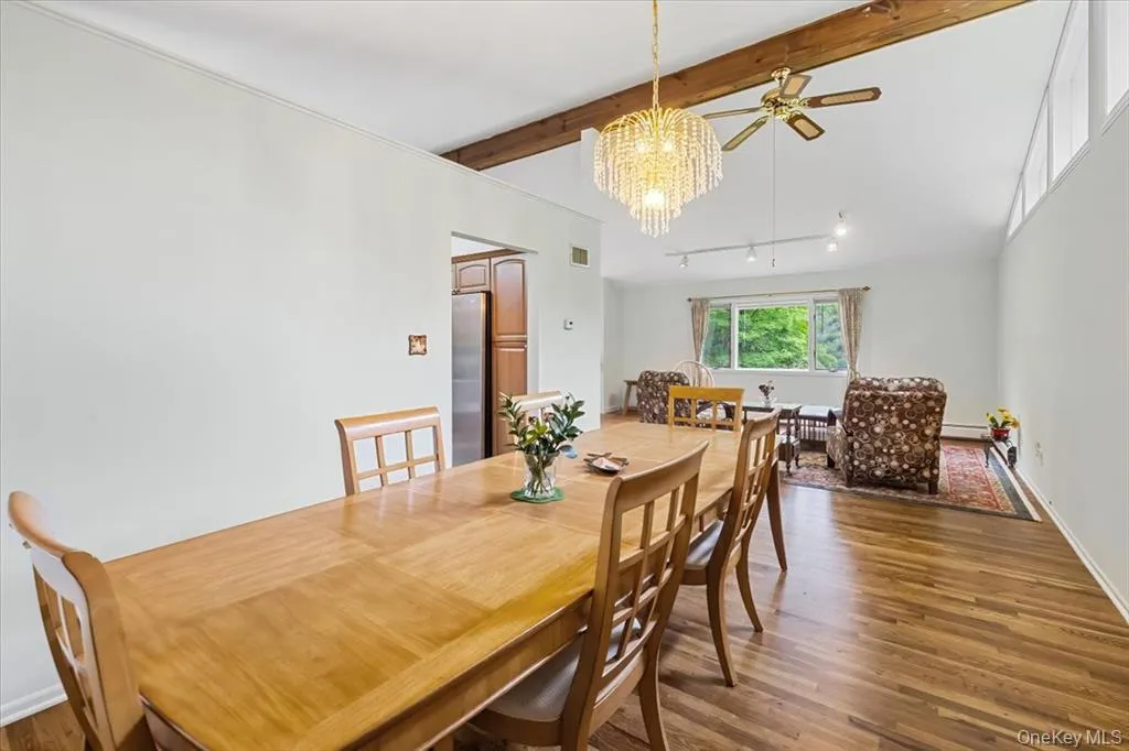Dining area with wood finished floors, ceiling fan, beamed ceiling, and a chandelier Dining area with wood finished floors, ceiling fan, beamed ceiling, and a chandelier