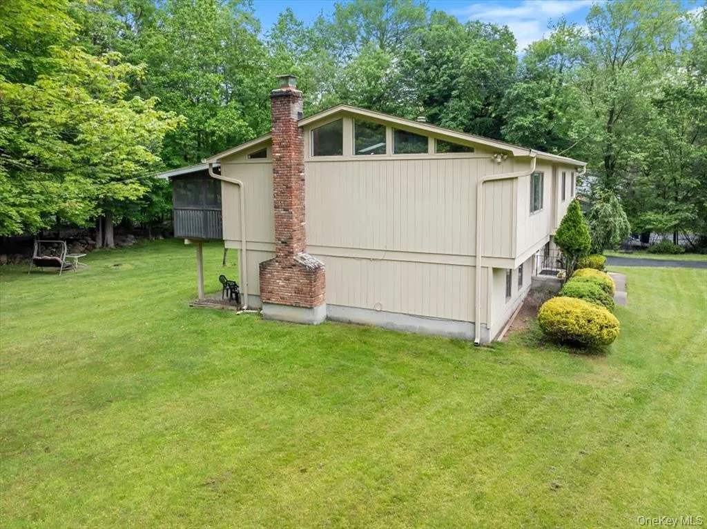 View of side of home with a lawn, a chimney, and view of scattered trees View of side of home with a lawn, a chimney, and view of scattered trees