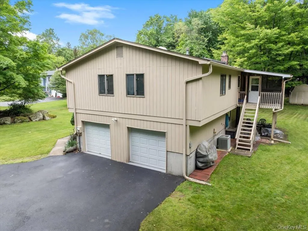 View of property exterior featuring stairs, a lawn, asphalt driveway, an attached garage, and a chimney View of property exterior featuring stairs, a lawn, asphalt driveway, an attached garage, and a chimney